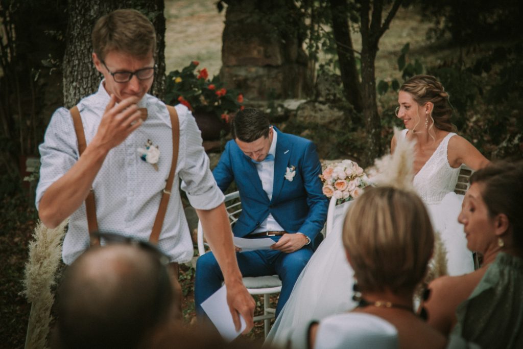 Un homme vient de faire un discours au mariage de son frère. Lui et son frère (le marié) pleurent. La mariée, assise à côté de son mari, rit de la situation. 
Je suis photographe de mariage basé en Suisse.