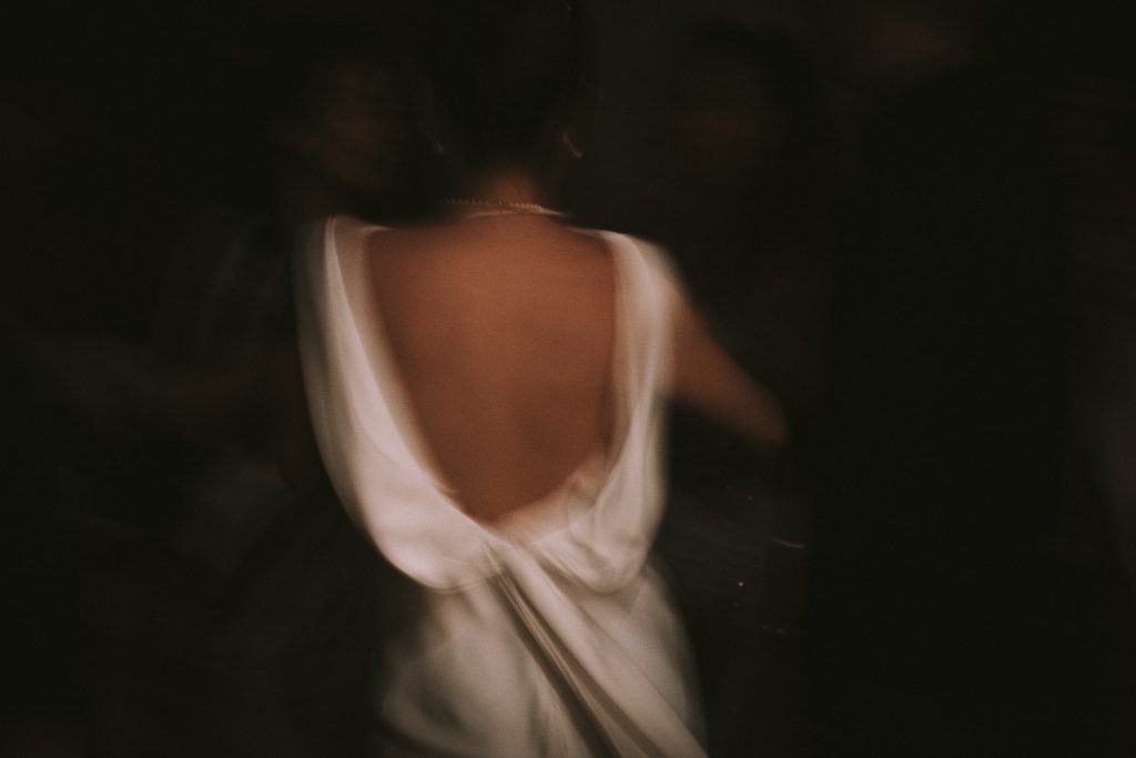 Une mariée danse, on voit sa robe de mariée. La photo est floue pour montrer le mouvement.